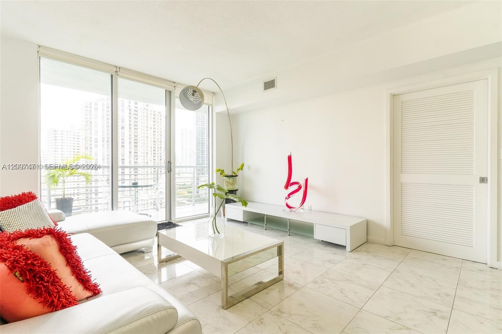 Living area featuring floor-to-ceiling glass sliding doors, stone-finish tile flooring, and a louvered interior door