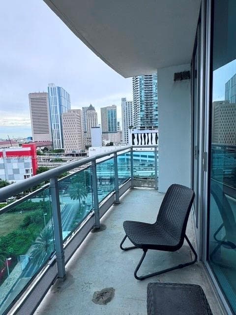 Private covered balcony featuring concrete flooring and a glass-paneled metal railing