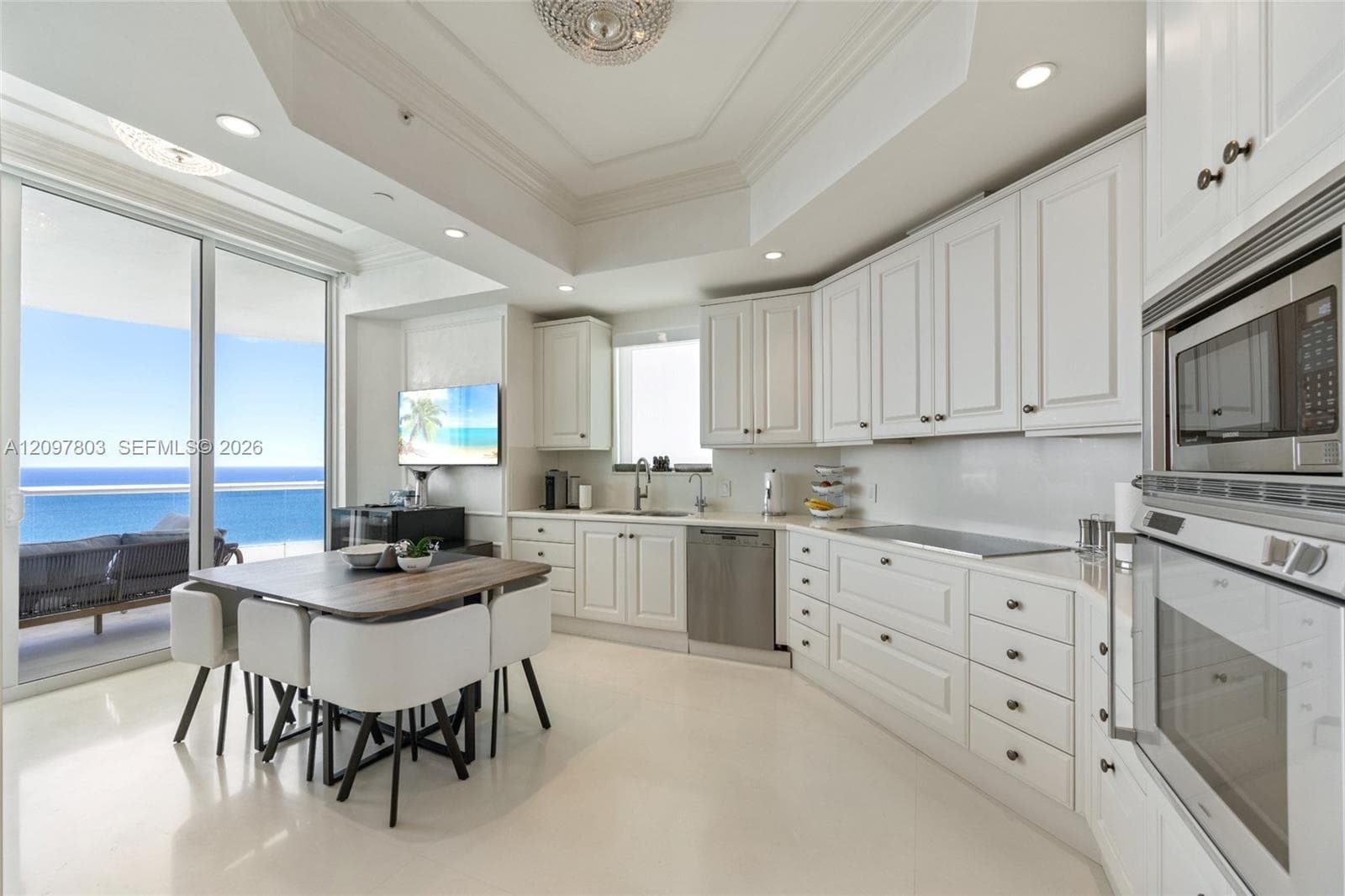 Kitchen featuring white cabinetry, recessed lighting, tray ceiling, stainless steel built-in appliances, and light-toned flooring