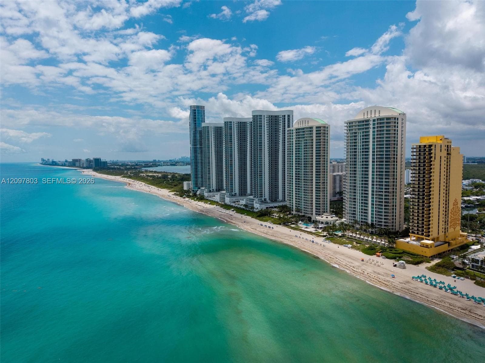 Aerial perspective of high-rise towers featuring direct oceanfront positioning, expansive coastal frontage, and proximity to sandy shoreline