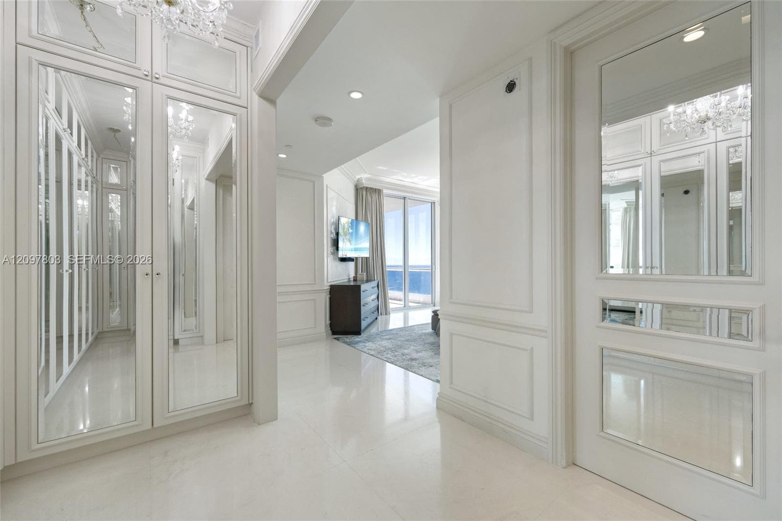 Custom floor-to-ceiling cabinetry with mirrored doors, millwork wall paneling, polished stone-finish flooring, and recessed lighting
