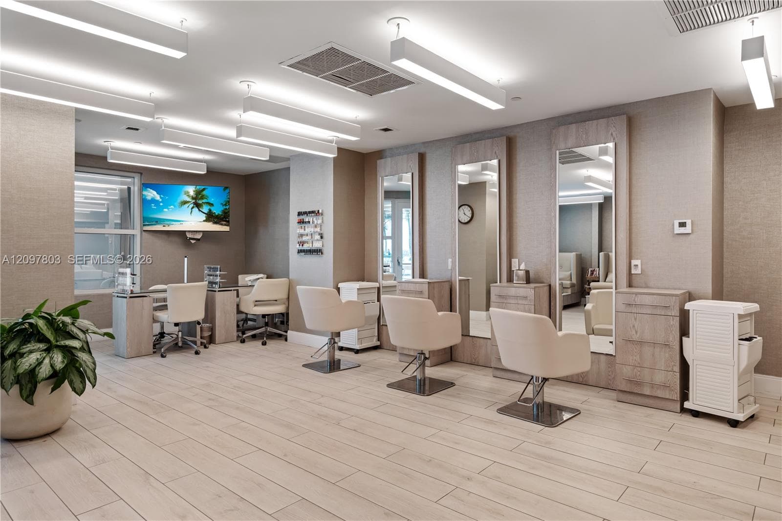 Spacious facility featuring light wood-finish flooring, full-length mirrors integrated into wood cabinetry, and overhead linear lighting fixtures