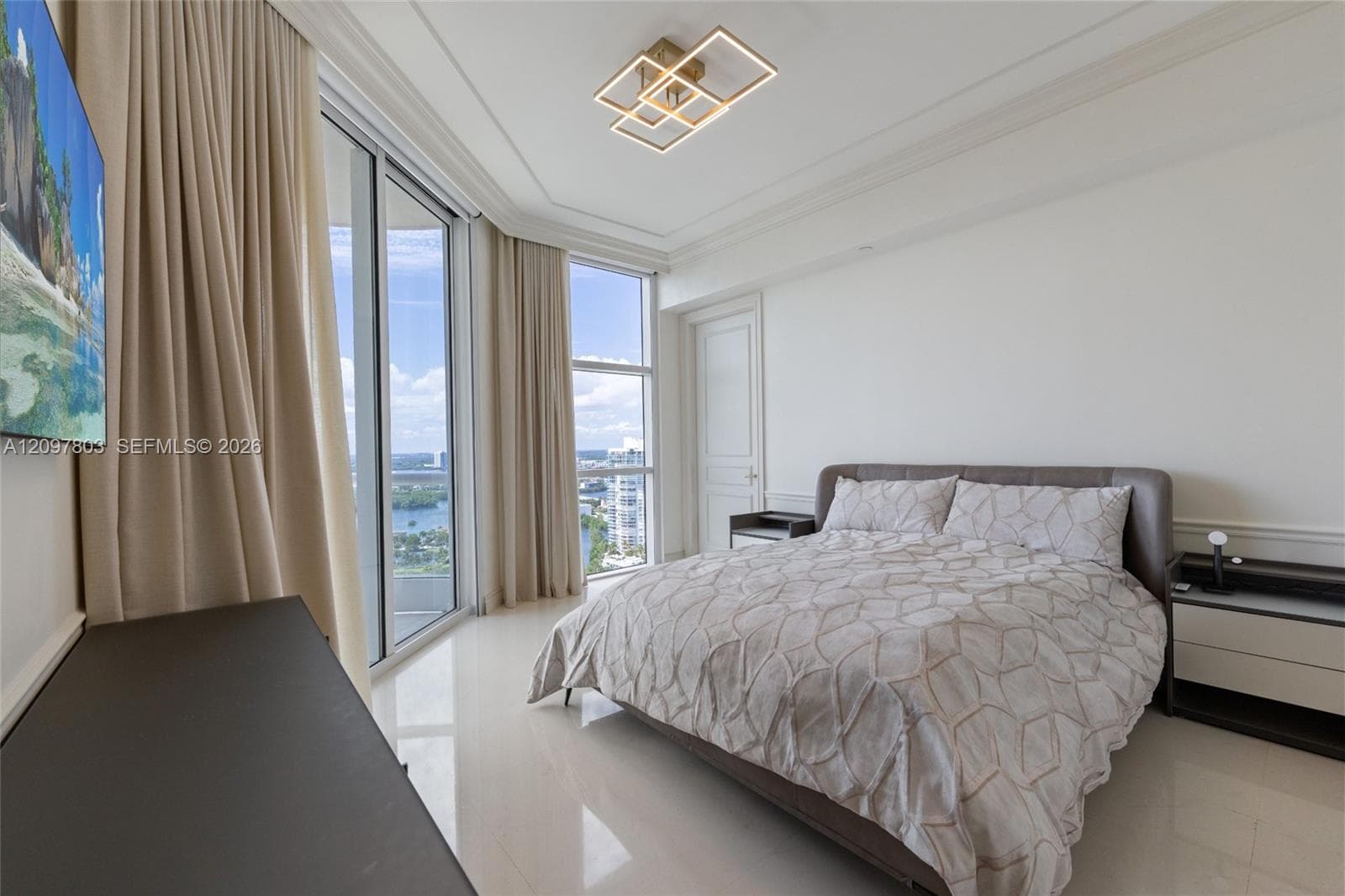 Floor-to-ceiling windows, polished tile flooring, geometric LED light fixture, tray ceiling, and crown molding