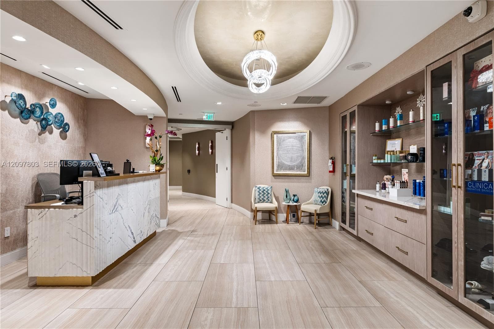 Reception area featuring a stone-faced desk, recessed ceiling with a gold-leaf domed medallion, custom built-in cabinetry with integrated display glass, and large-format tile flooring