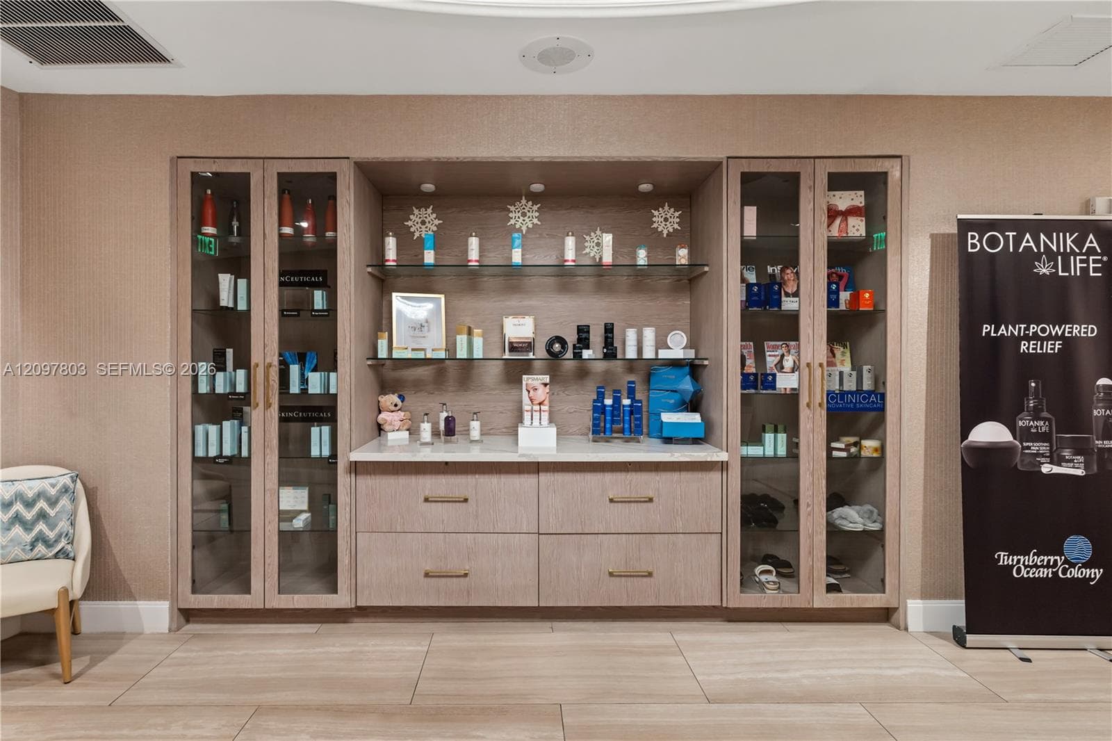 Built-in cabinetry featuring light wood-finish veneer, glass-front display towers, stone-surface countertop, and recessed display lighting