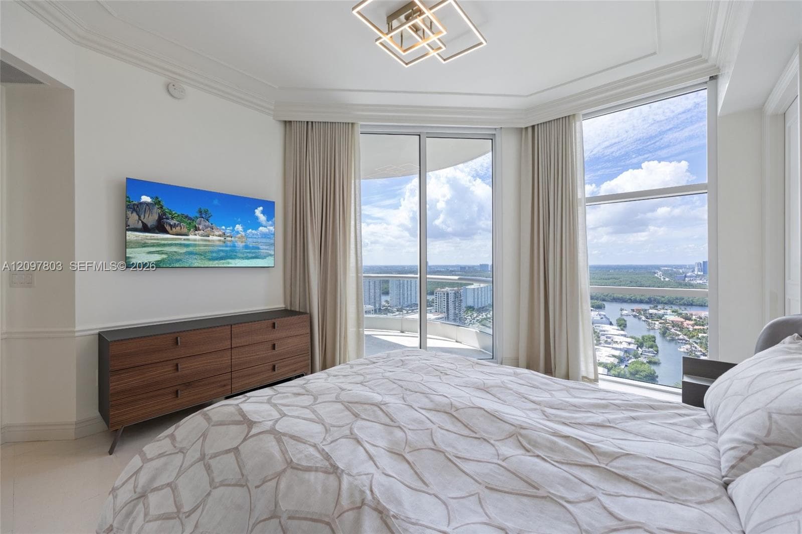 Floor-to-ceiling windows, geometric flush-mount lighting, crown molding, and neutral tile flooring