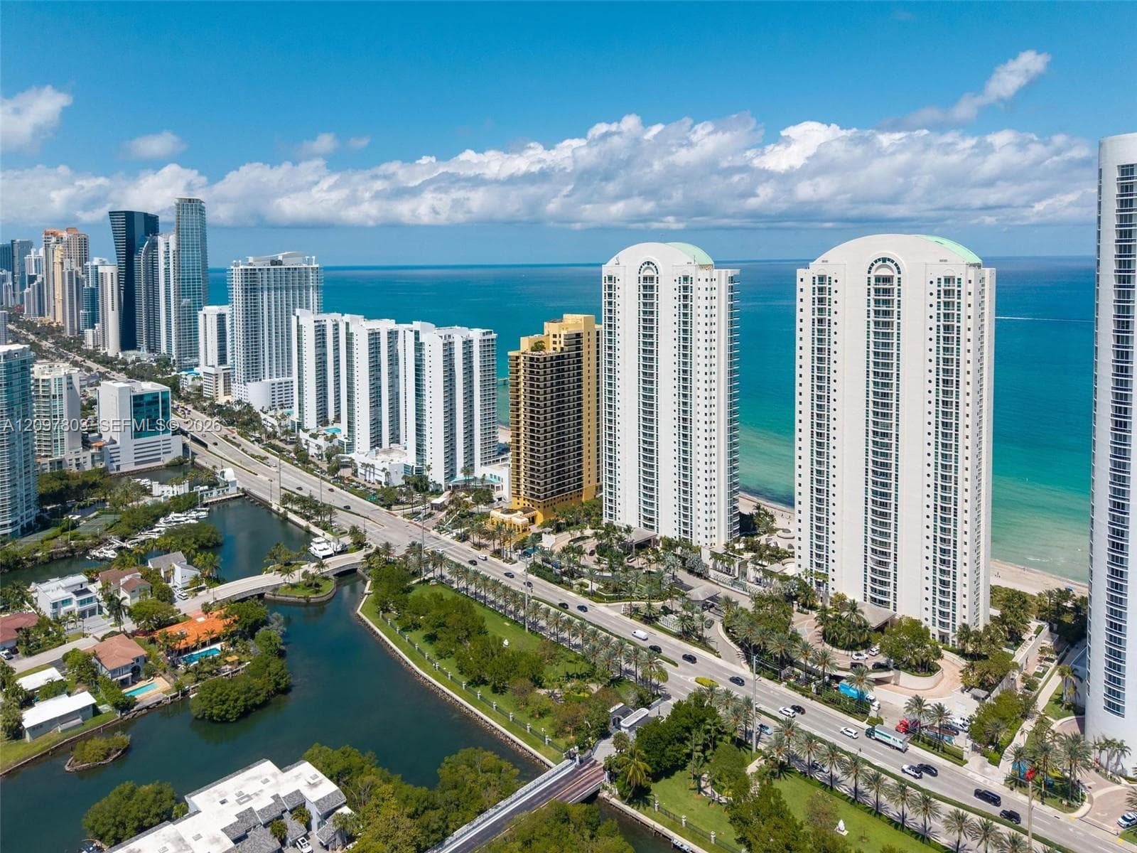 Aerial perspective featuring coastal high-rise architecture, proximity to the oceanfront, waterway access, and established landscaping