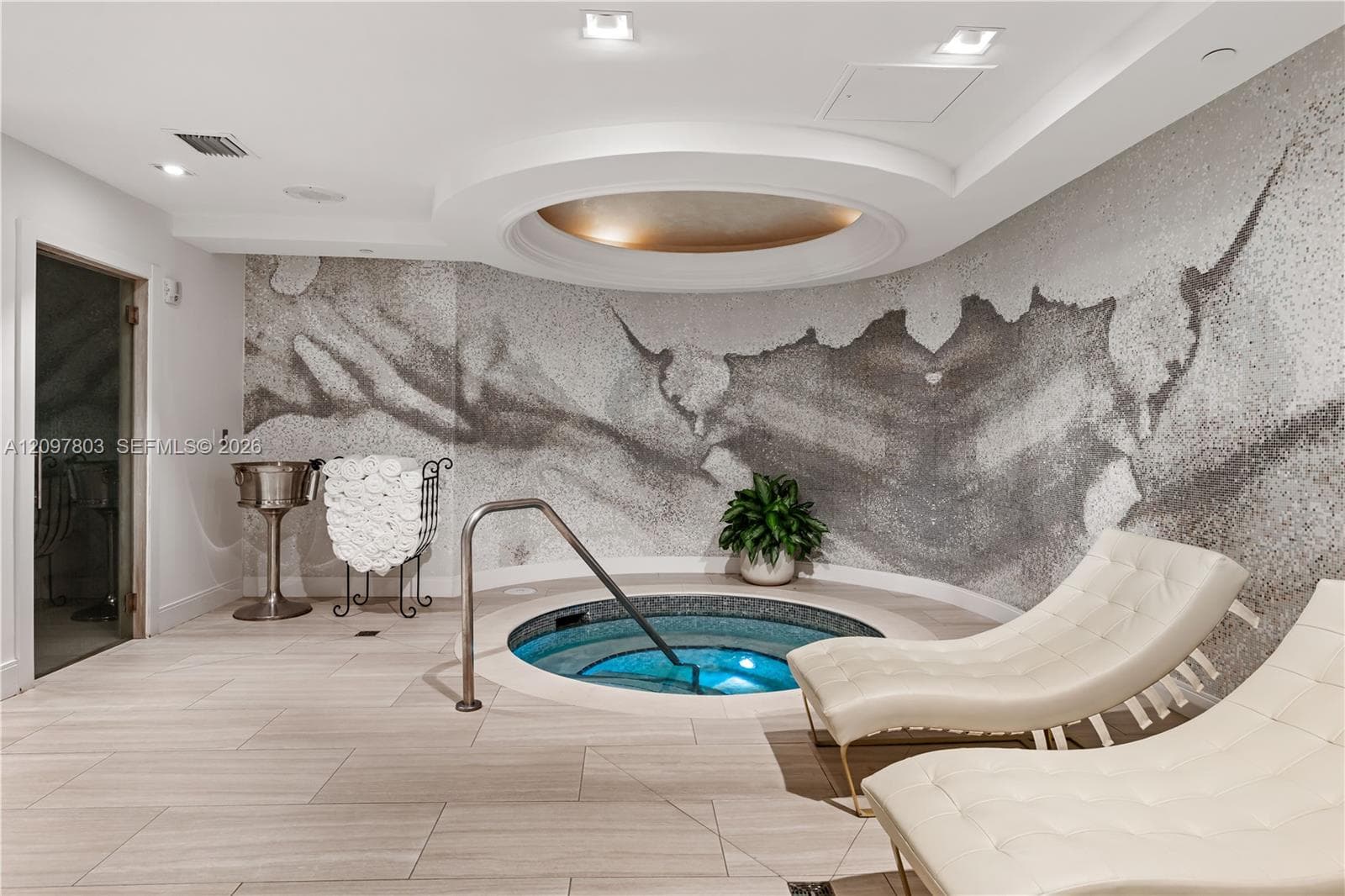 In-ground spa featuring a circular recessed ceiling, custom stone-tiled wall accent, integrated recessed lighting, and stone-finish flooring