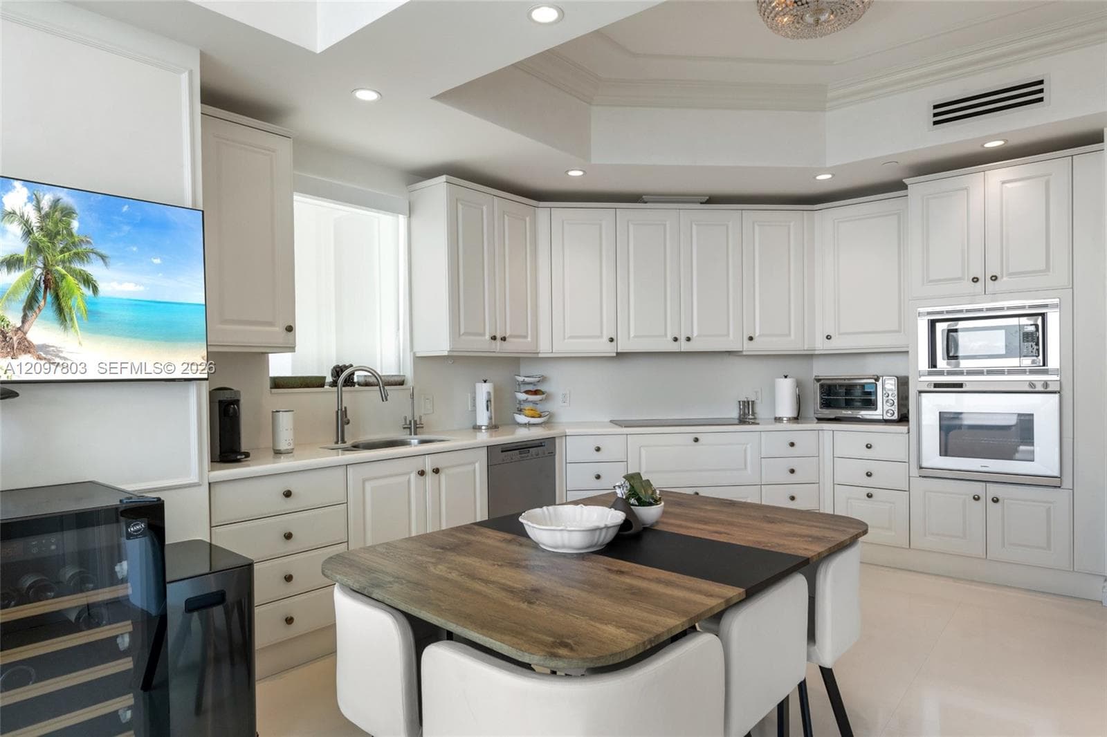 Kitchen featuring white Shaker-style cabinetry, a built-in double oven, recessed tray ceiling lighting, and a kitchen island with a wood-finish surface