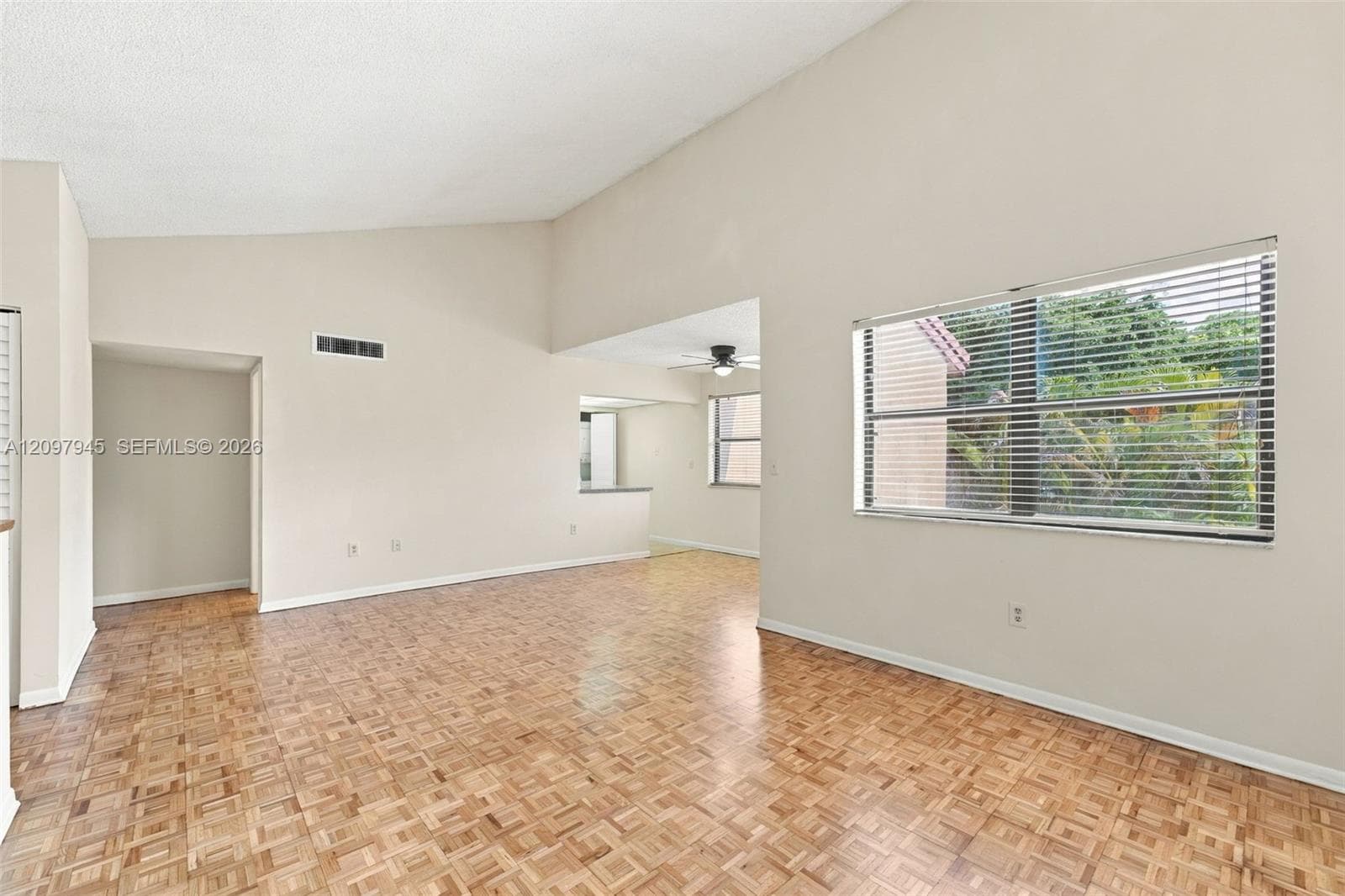 Vaulted ceilings, wood-finish parquet flooring, and large windows with horizontal blinds