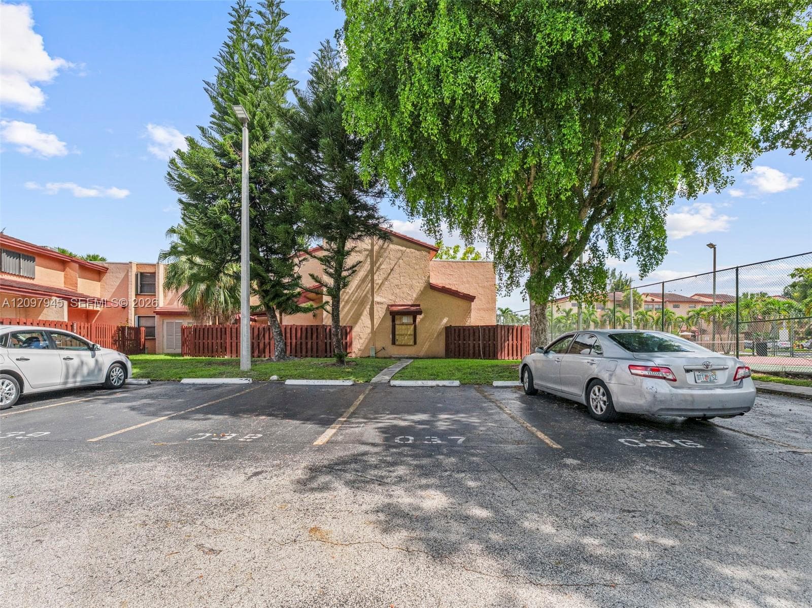 Asphalt parking area with designated numbered spaces and mature tree canopy