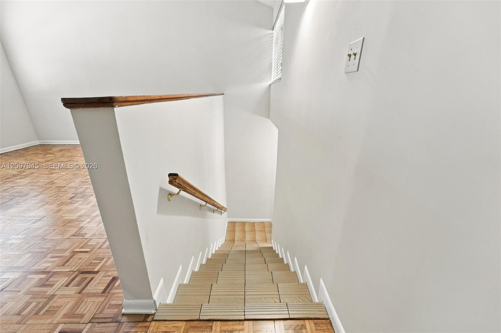 Parquet wood-finish flooring, staircase featuring tiled treads, and a wooden handrail