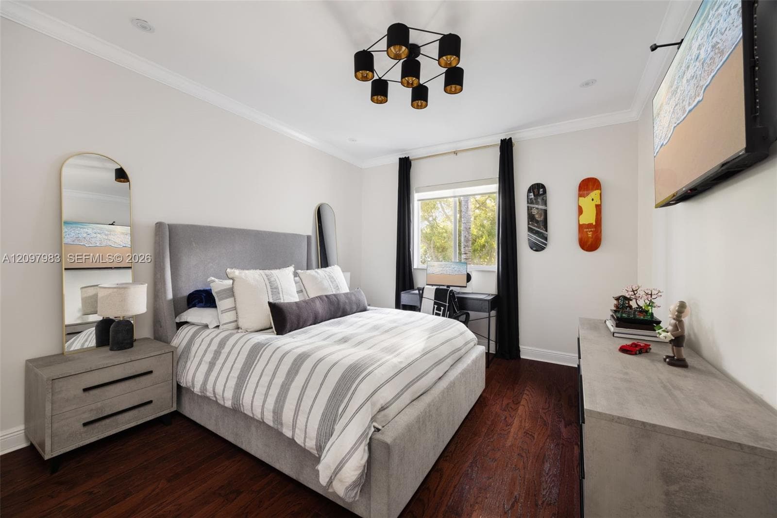 Room featuring dark wood-finish flooring, crown molding, and a modern multi-light chandelier