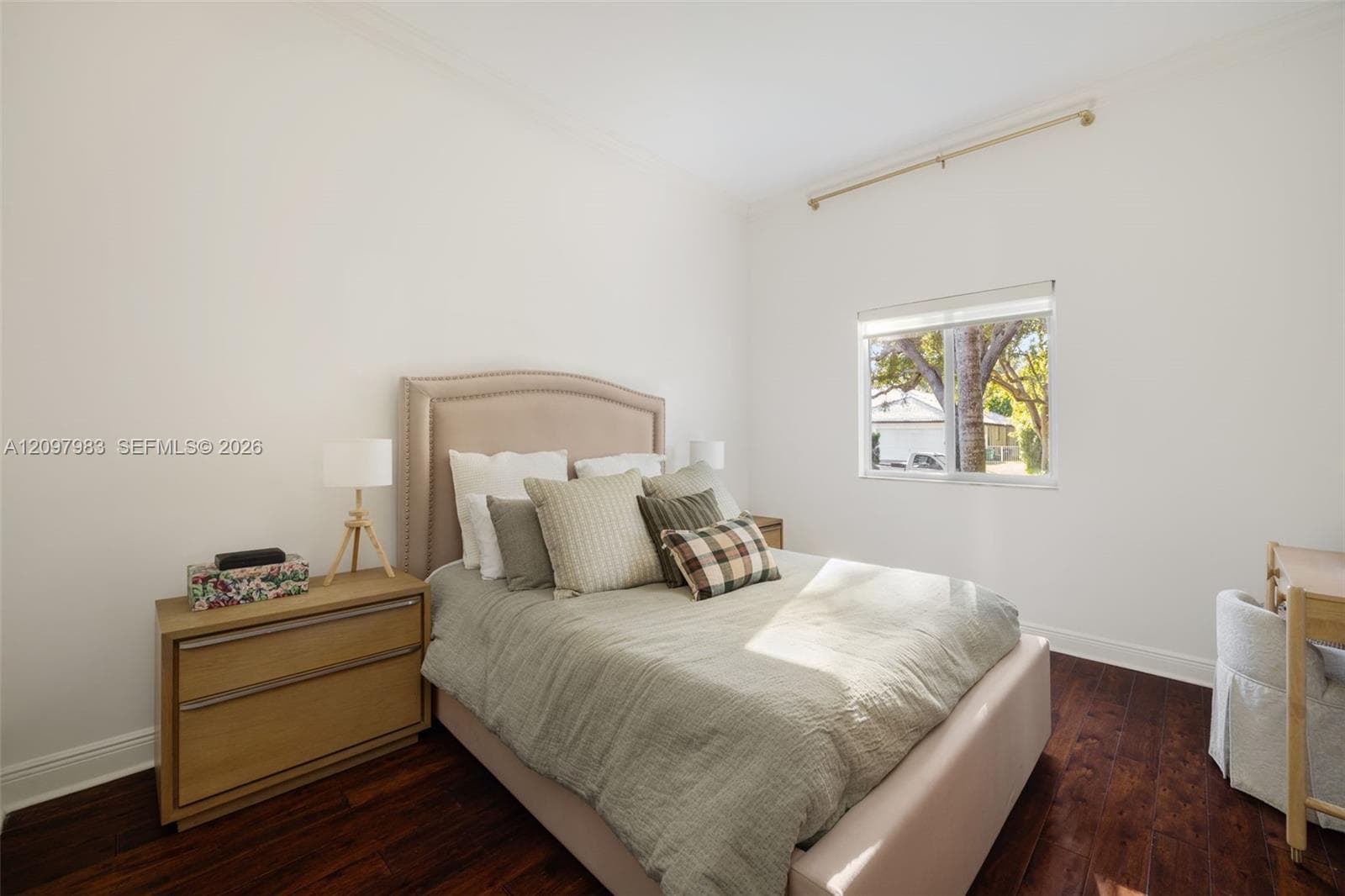 Bedroom featuring dark-stained wood-finish flooring, neutral walls, crown molding, and a single window with a curtain rod