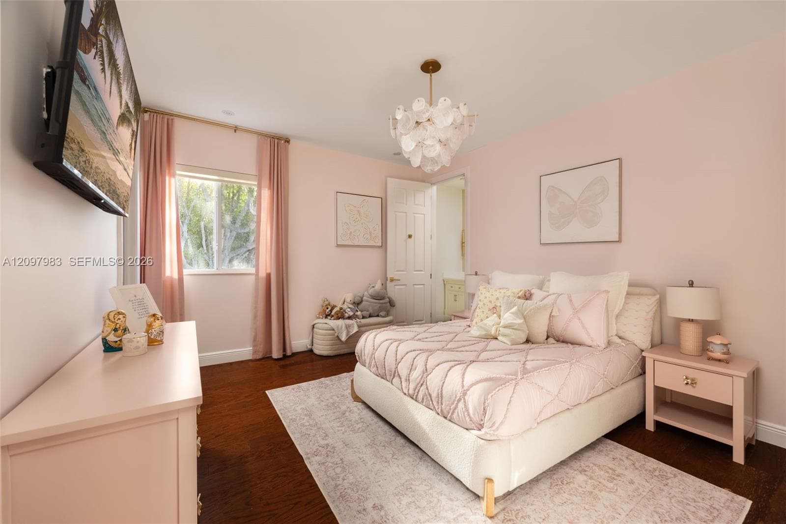 Wood-finish flooring, multi-pane window with natural light, decorative gold-tone chandelier with layered glass accents, and a four-panel interior door