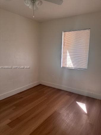 Room featuring wood-finish flooring, neutral wall paint, and a ceiling-mounted light fixture with a fan