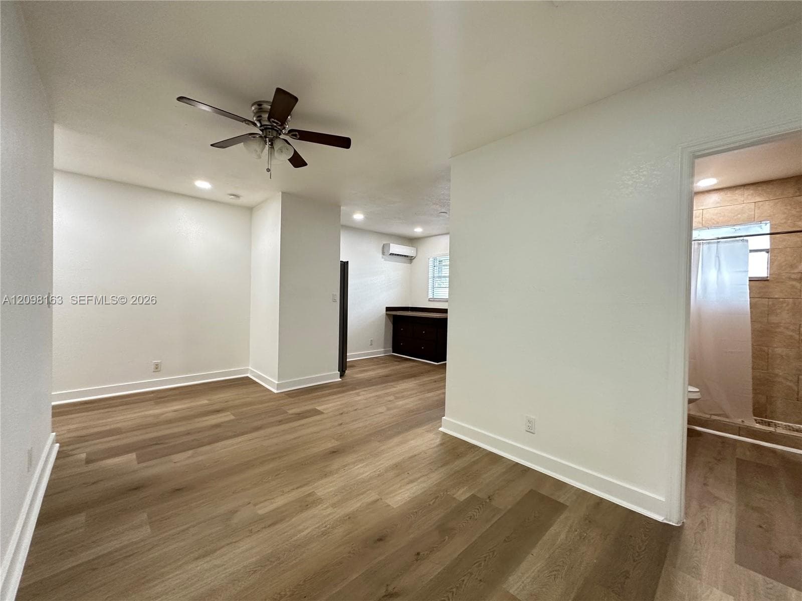 Interior space featuring wood-finish flooring, a ceiling fan with integrated lighting, recessed lighting, and a ductless mini-split air conditioning unit