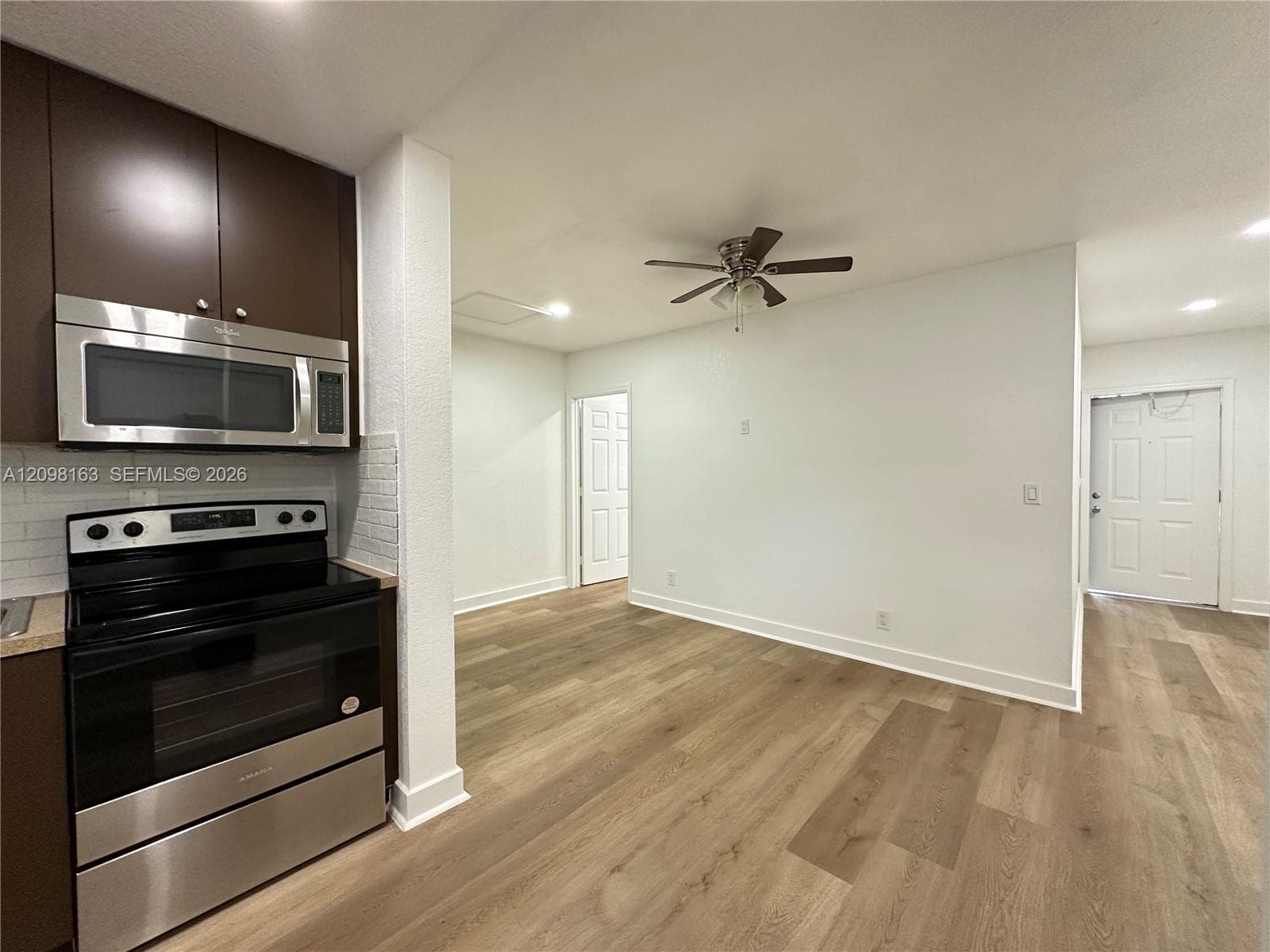 Kitchen area featuring dark-tone cabinetry, stainless steel microwave, stainless steel range, and wood-finish flooring