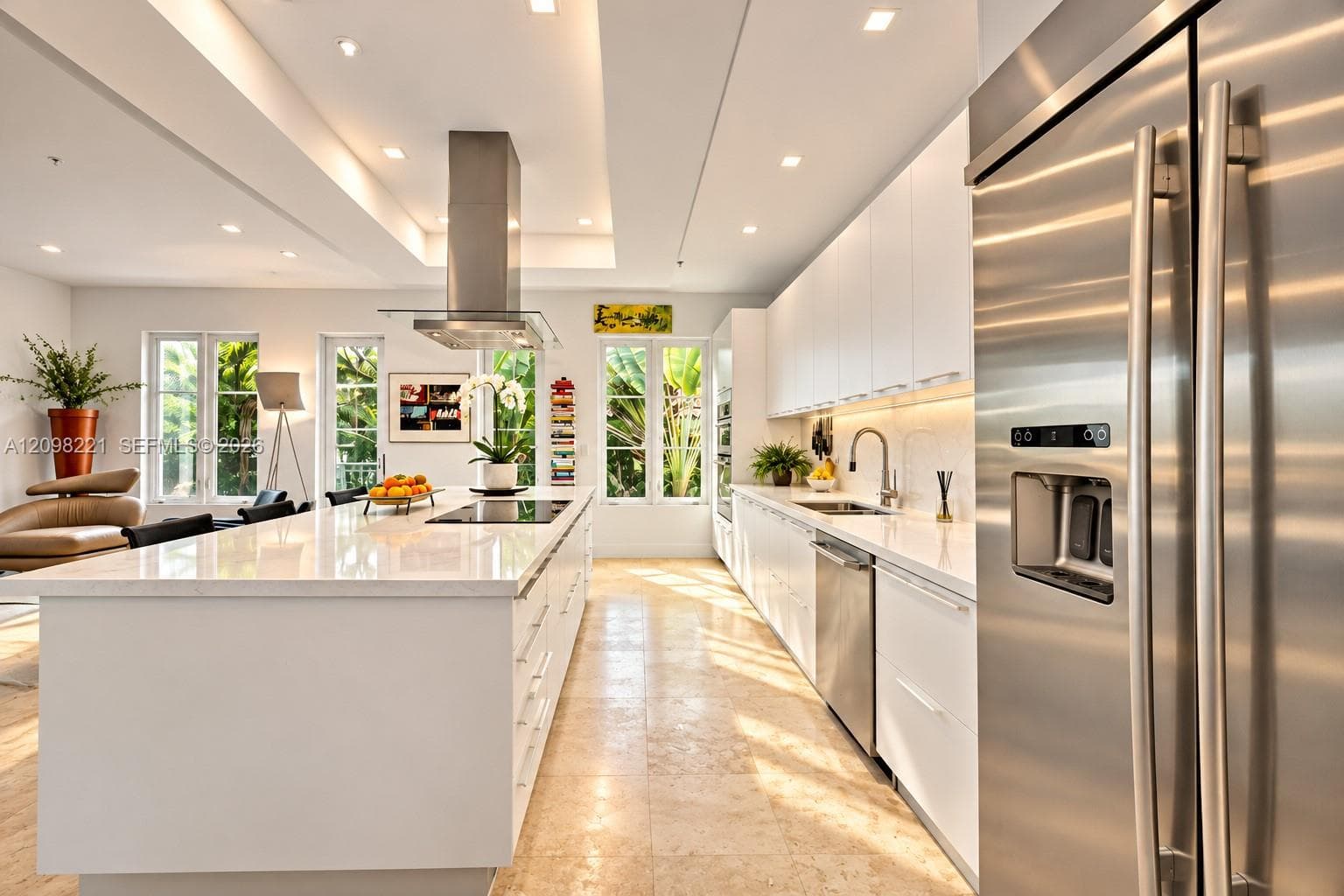 Modern kitchen featuring flat-panel cabinetry, a central island with a solid-surface countertop, stainless steel appliances, recessed ceiling lighting, and stone flooring