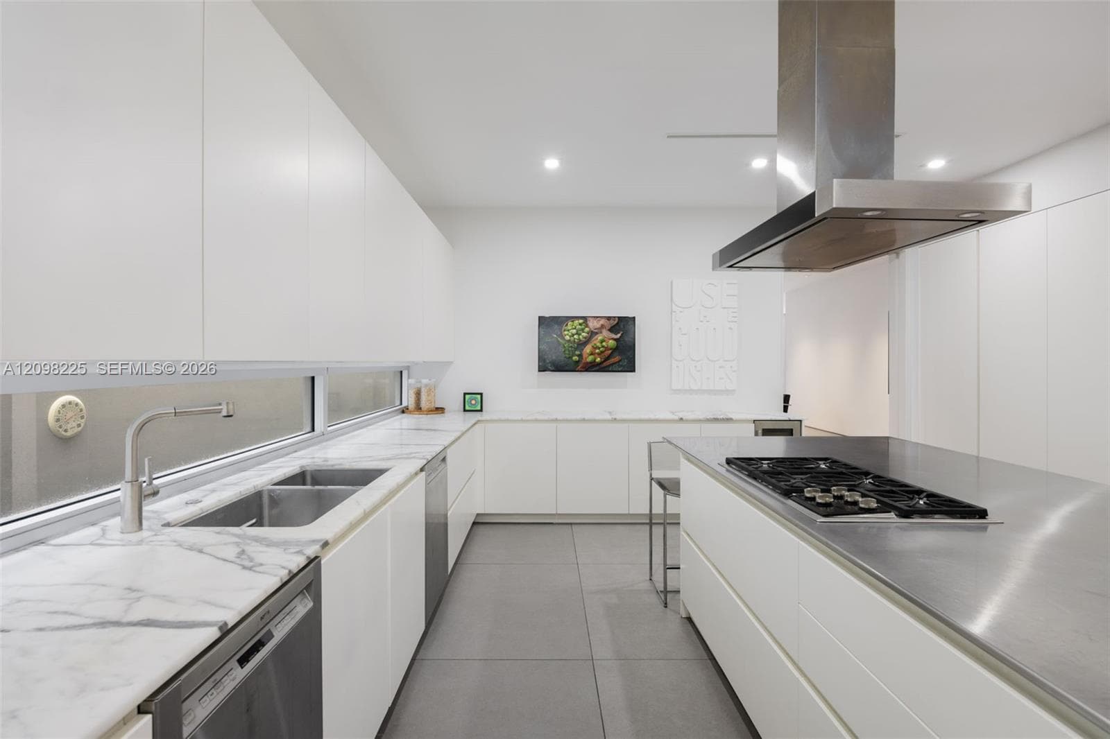 Contemporary kitchen featuring flat-panel cabinetry, stone countertops, stainless steel island cooktop with hood, and large-format tile flooring