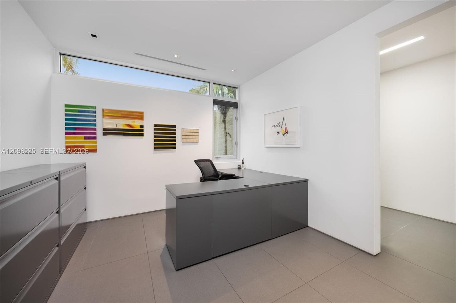 Minimalist room featuring large-format neutral tile flooring, high ceilings with recessed linear lighting, and clerestory windows