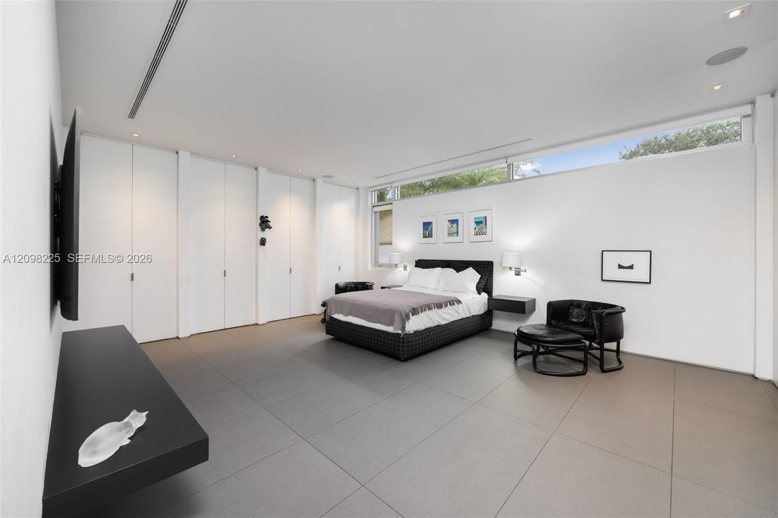 Expansive room featuring large-format tile flooring, built-in floor-to-ceiling storage cabinetry, recessed lighting, and horizontal clerestory windows