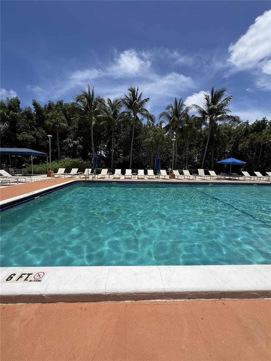 Swimming pool with concrete perimeter, tiled water line, and surrounding hardscape deck