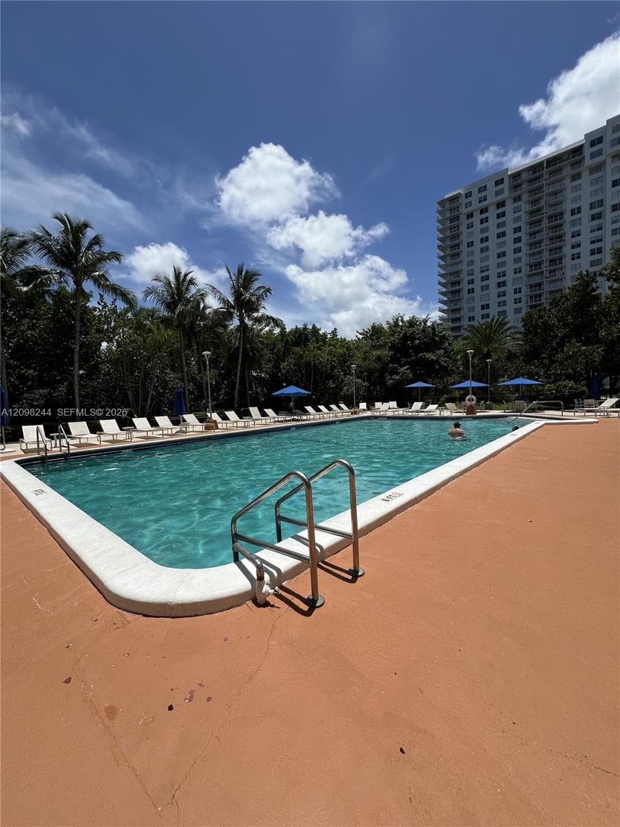 Rectangular swimming pool with integrated metal handrails, white coping, and surrounding concrete deck