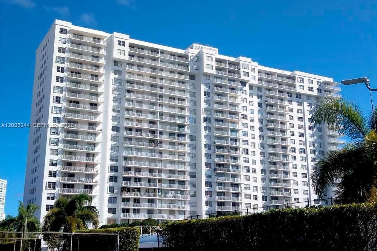 High-rise residential exterior featuring a white facade, uniform horizontal balcony tiers, and metal railings
