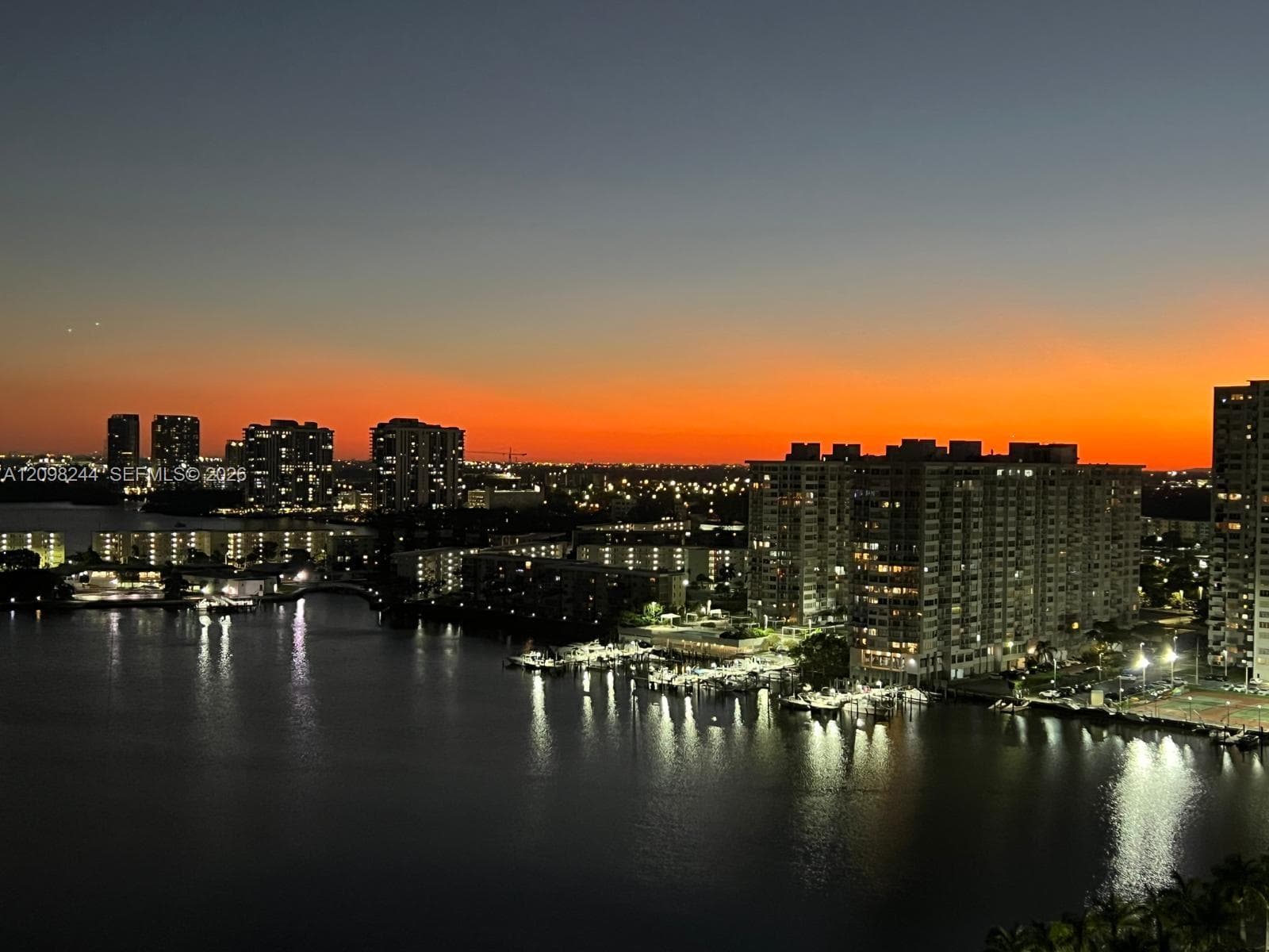 Panoramic water and urban skyline backdrop featuring high-rise architecture, a marina, and bridge infrastructure