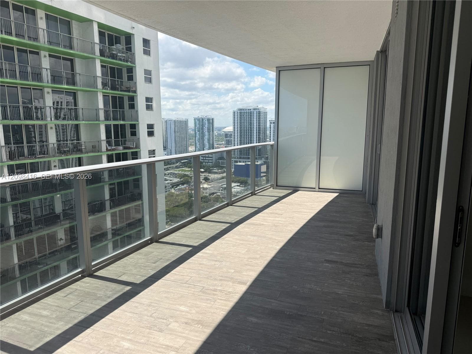 Expansive balcony featuring tile flooring, glass-panel railings, and a sliding glass door entry