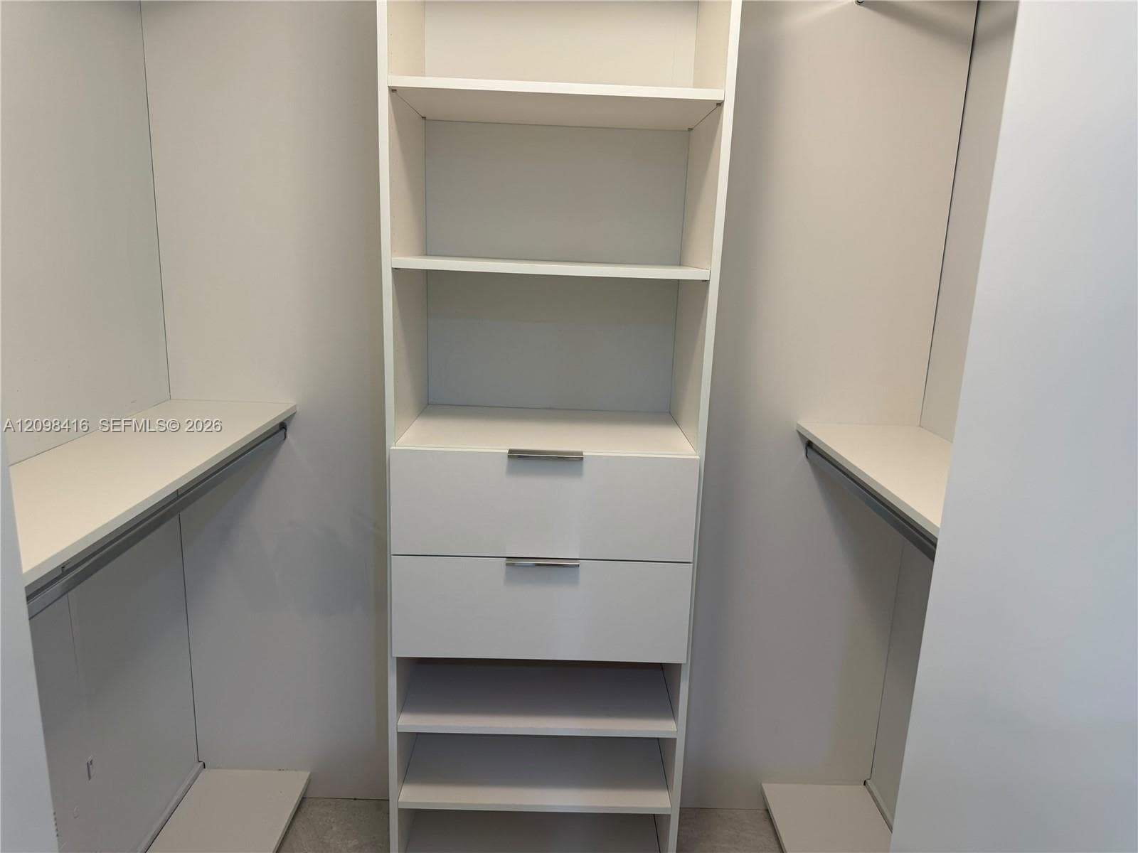 Custom closet system with integrated shelving, two drawers with polished chrome hardware, and hanging rods