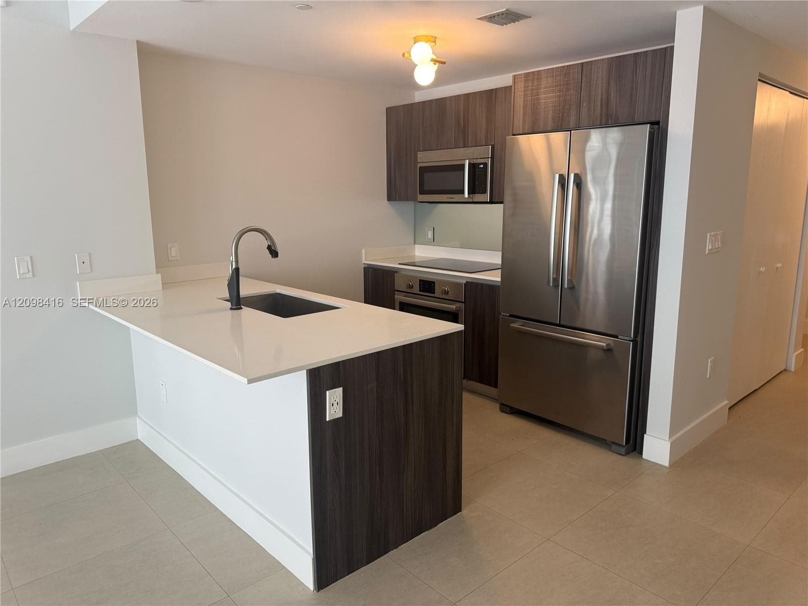 Kitchen featuring a peninsula with a dark-finish base, integrated sink, and gooseneck faucet