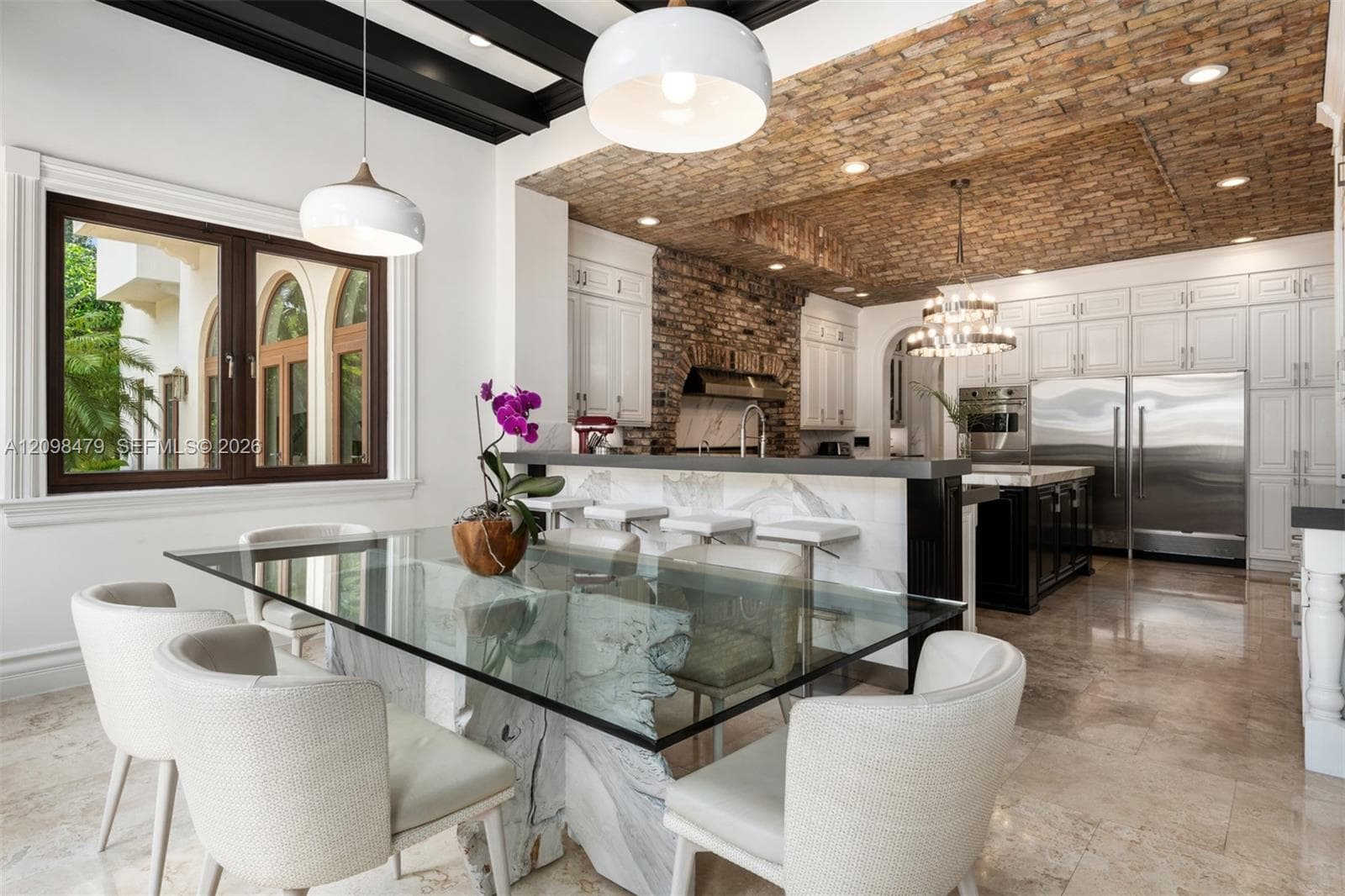 Recessed lighting, exposed brick ceiling, wood-frame window, paneled cabinetry, and stainless steel appliances