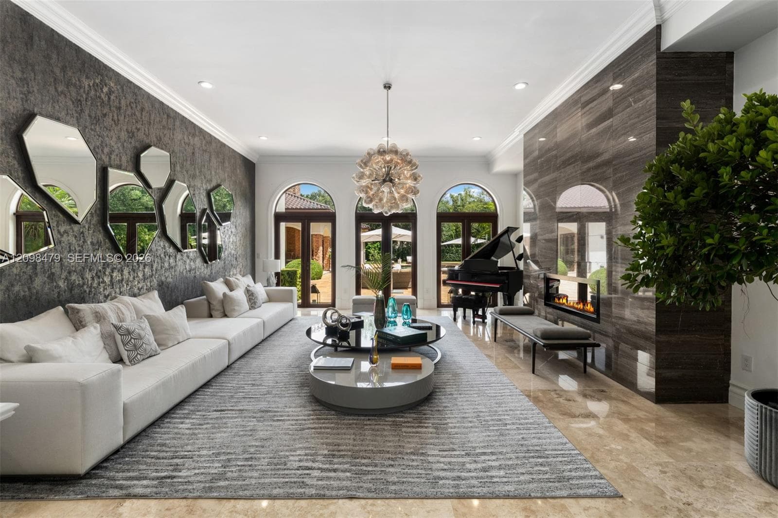 Recessed lighting, arched double doors, stone-finish flooring, accent wall with textured finish, and a dark stone fireplace with linear firebox