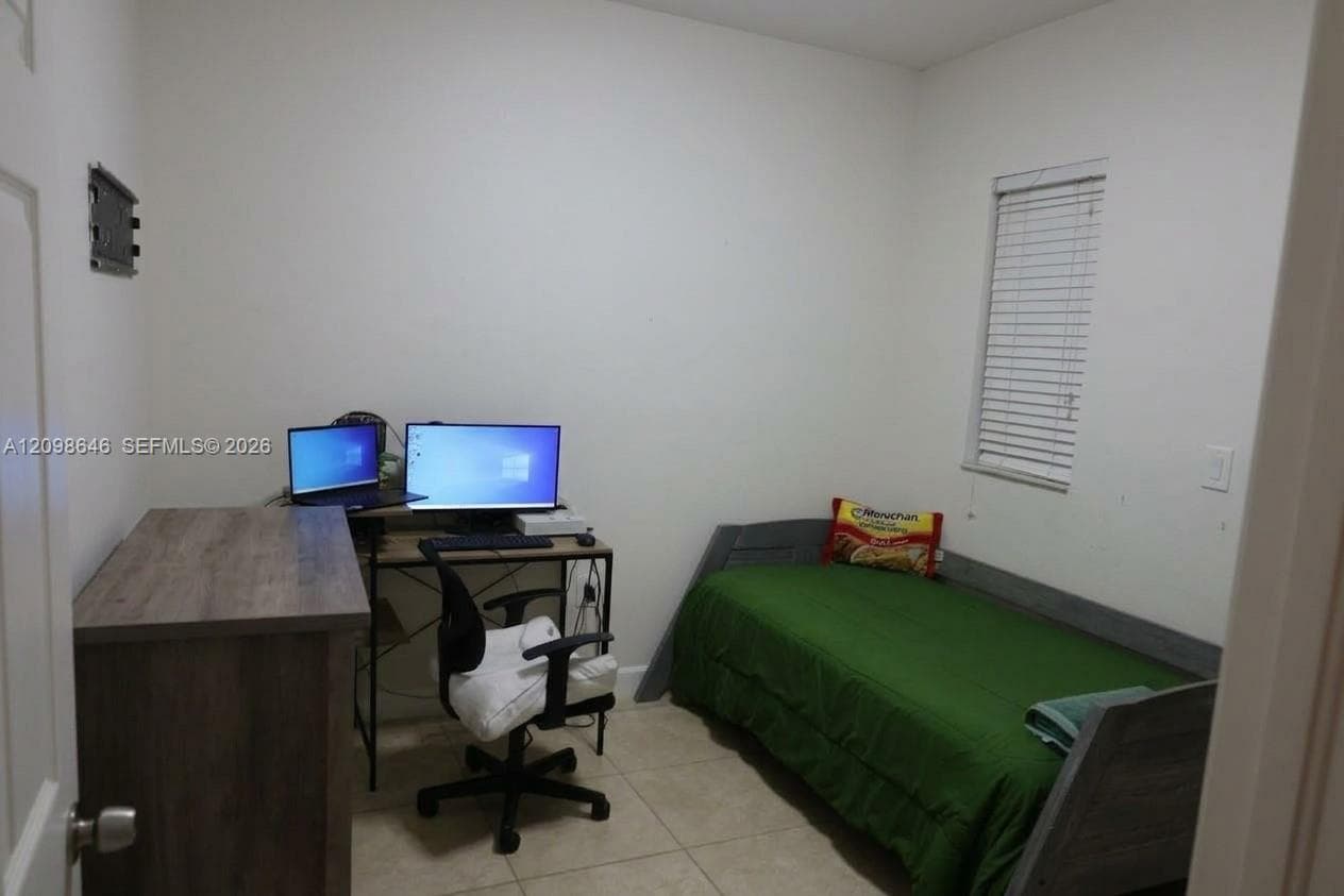 Room featuring neutral wall paint, tile flooring, and a single window with horizontal blinds