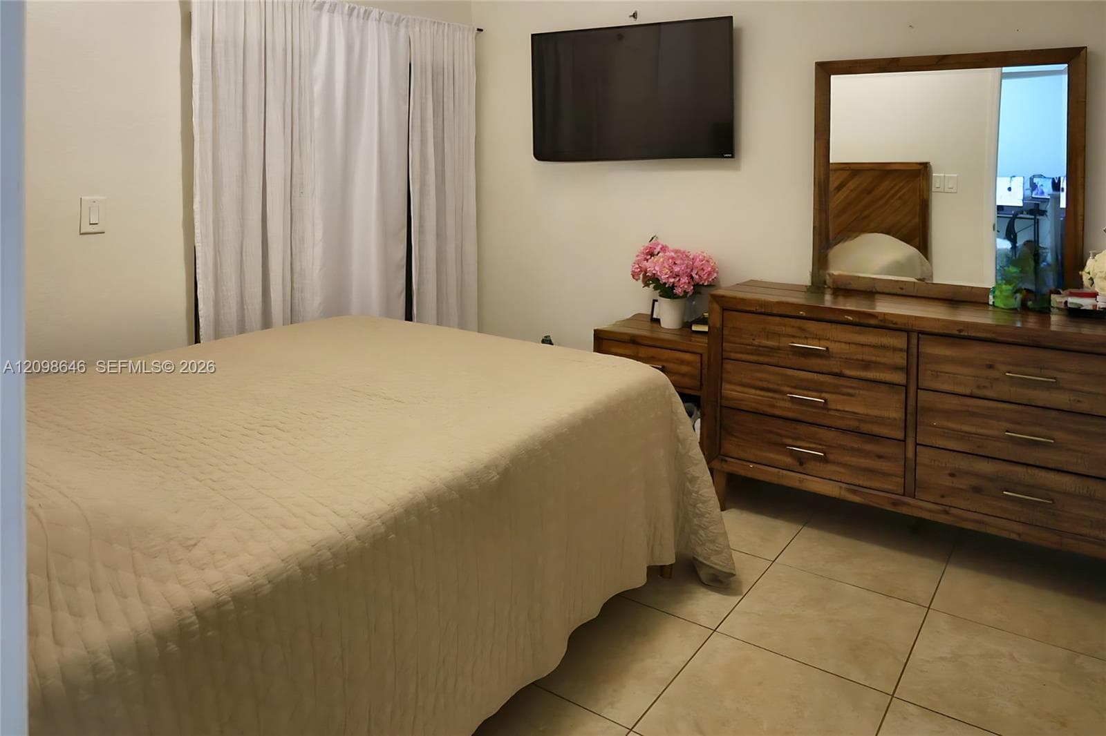 Neutral-toned ceramic tile flooring throughout, wall-mounted display area, and floor-to-ceiling drapery hardware