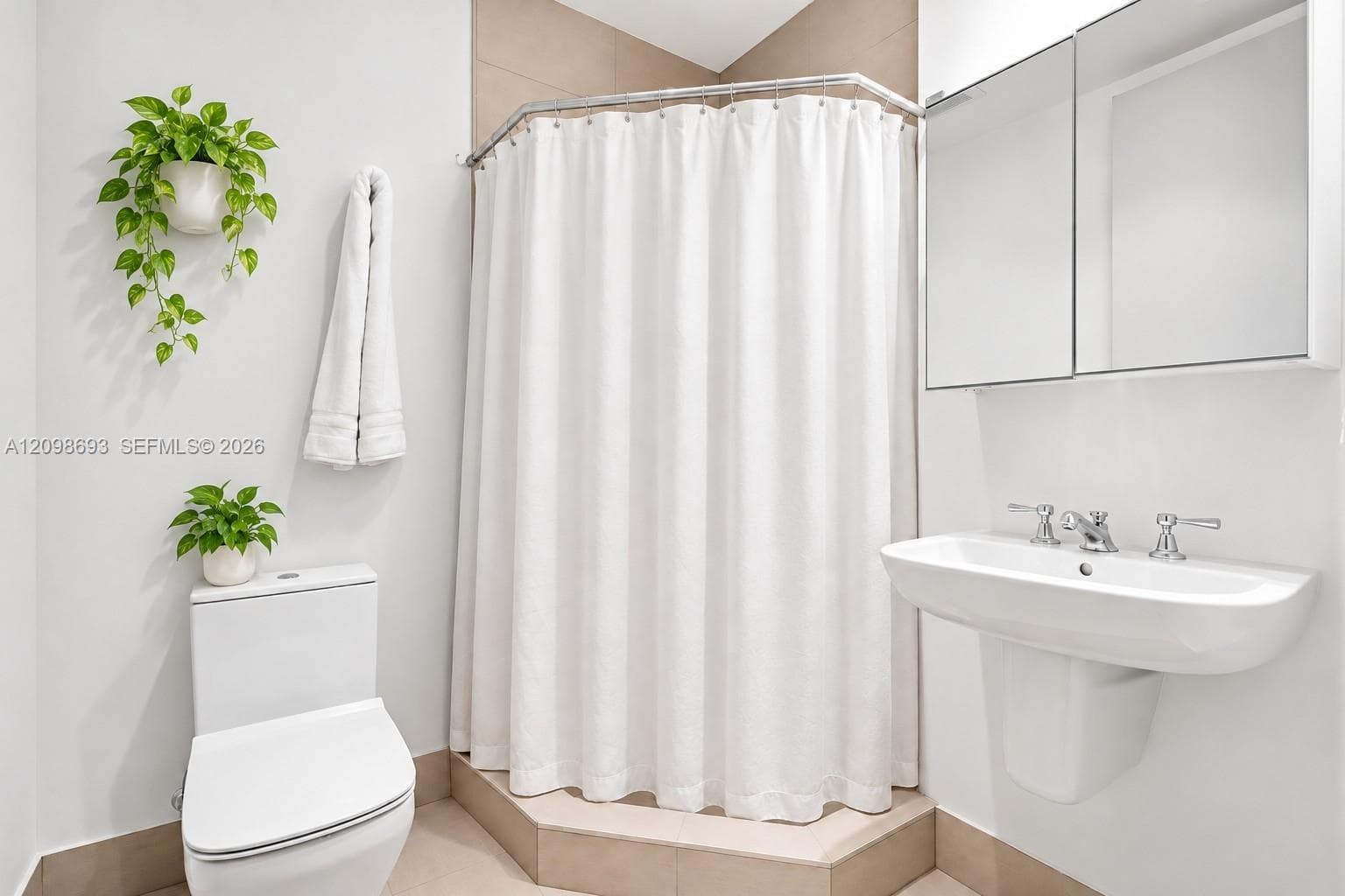 Wall-mounted pedestal sink with double-handle chrome faucet, corner shower enclosure, dual-door mirrored medicine cabinet, and low-profile toilet