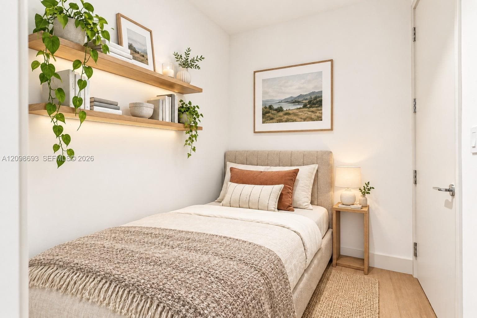 Wall-mounted wood shelving with integrated under-shelf lighting, light-tone wood-finish flooring, and a solid-core interior door with satin-nickel hardware