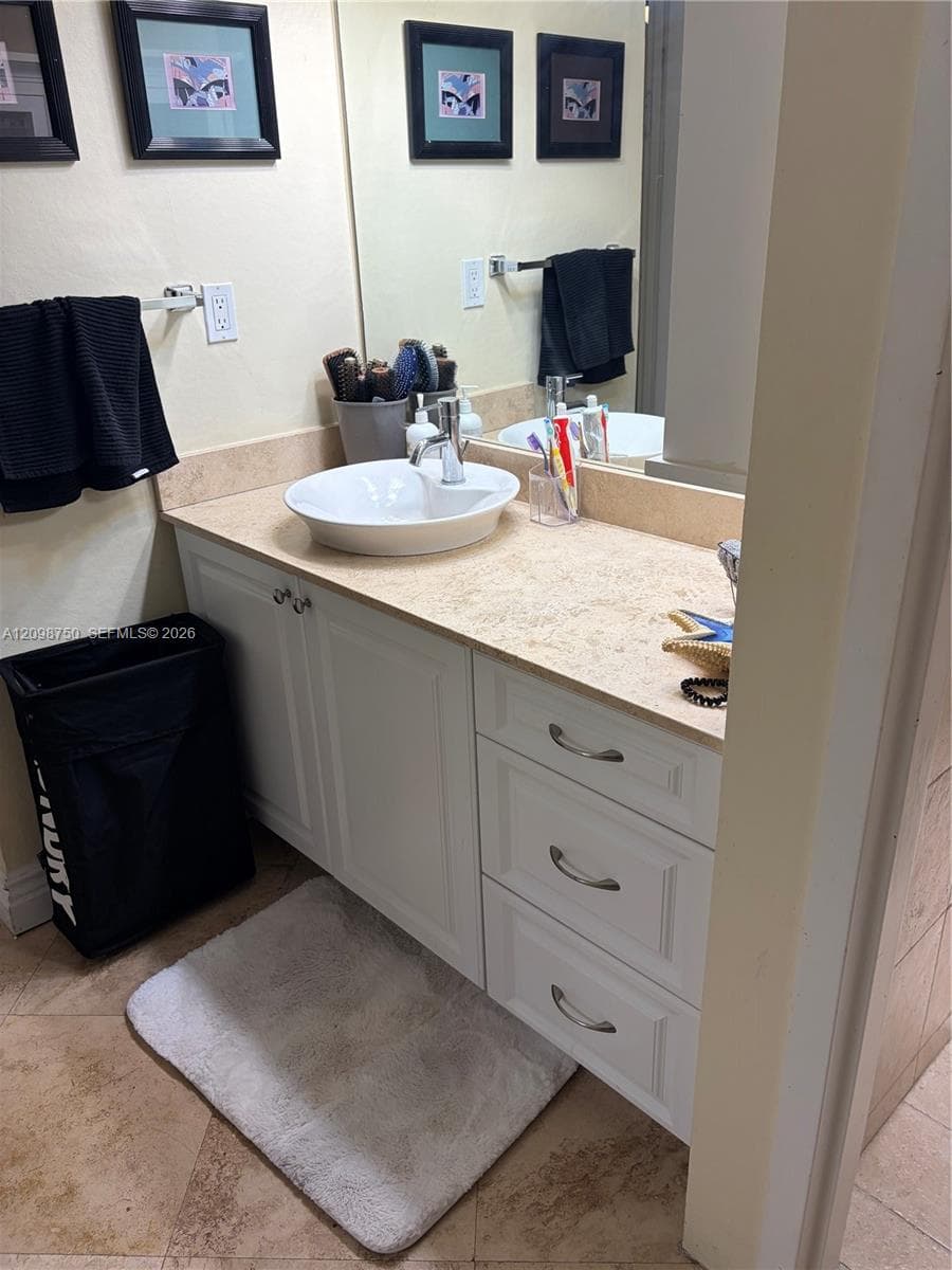 White vanity cabinet with brushed nickel hardware, stone-composite countertop, white vessel sink, polished chrome faucet, and integrated wall-to-wall vanity mirror
