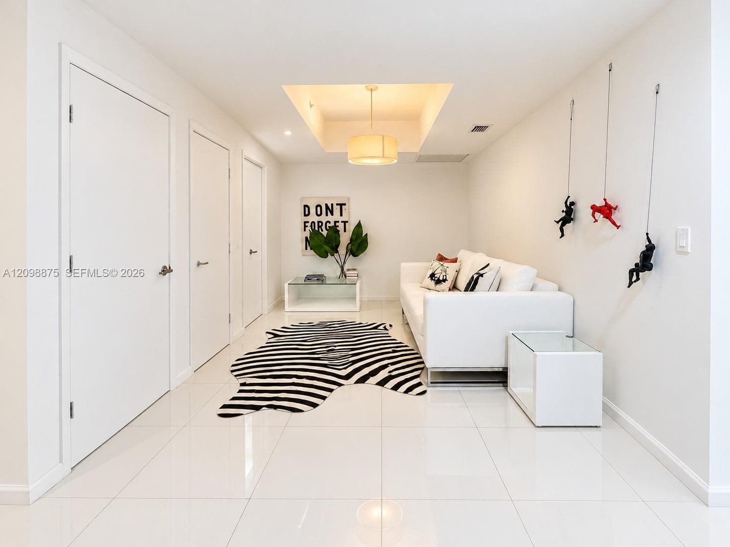 Recessed ceiling with integrated lighting, polished tile flooring, three white doors with contemporary hardware, and a dropped ceiling with a pendant light fixture