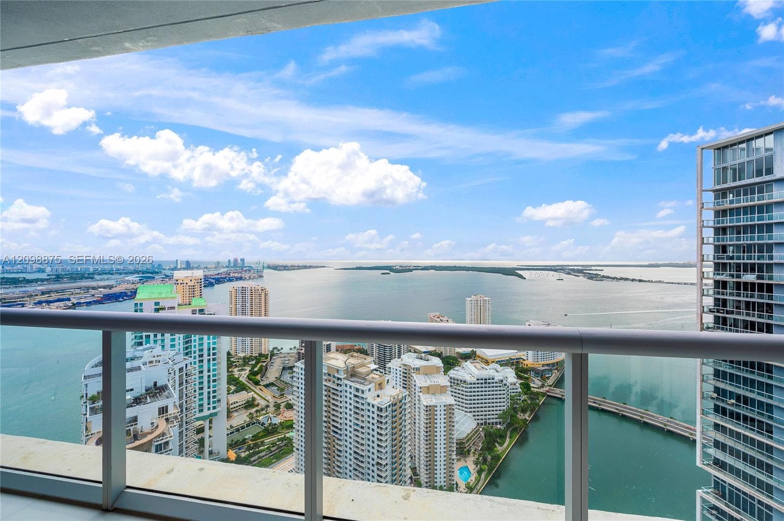 Expansive water scenery with city architecture, featuring a transparent balcony railing and a concrete balcony floor