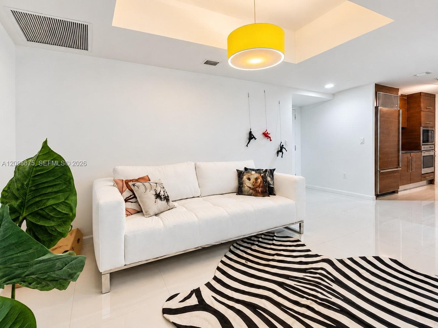 Recessed ceiling lighting, a contemporary yellow pendant light, white walls, and light-toned tile flooring