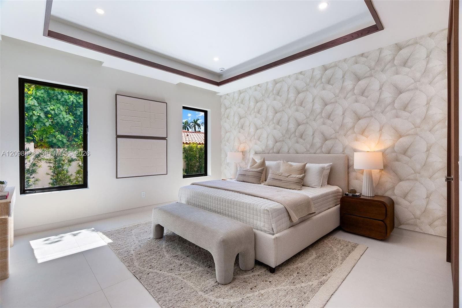Tray ceiling with dark wood-finish trim, patterned wallpaper accent wall, large picture windows with black frames, and neutral tile flooring