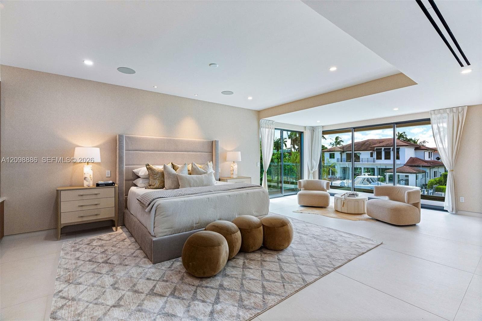 Large format tile flooring, recessed ceiling lighting, and floor-to-ceiling sliding glass doors featuring exterior waterfront scenery