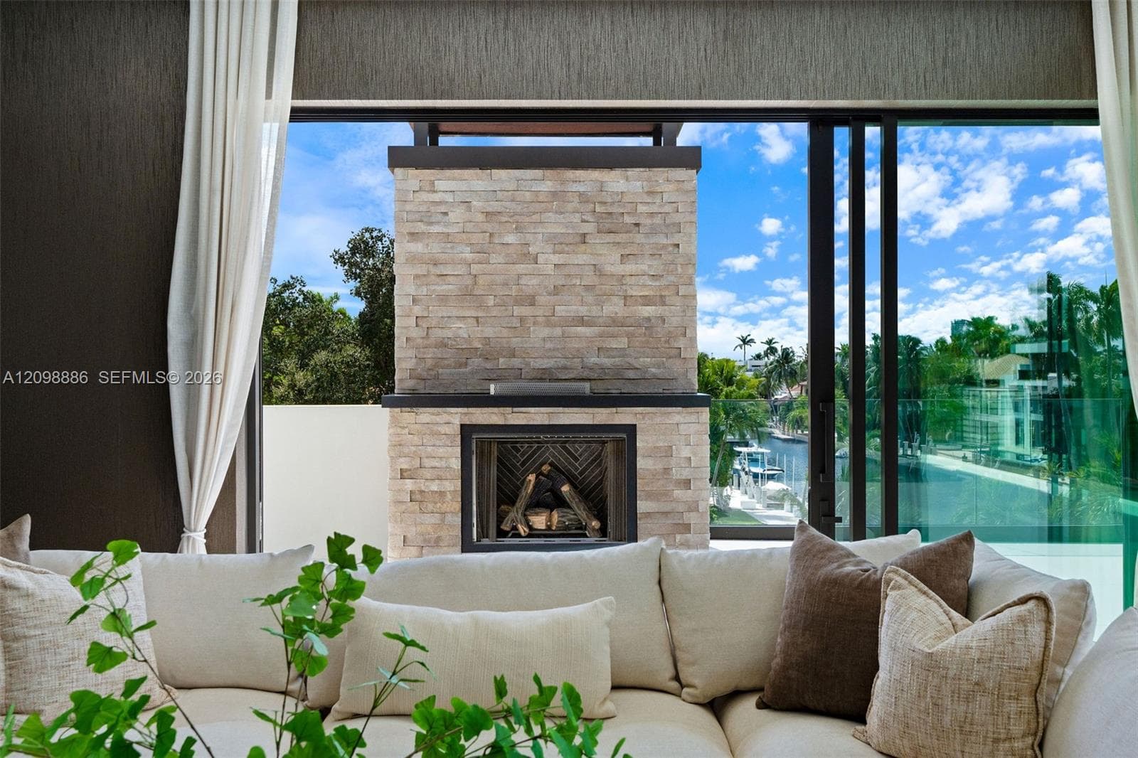 Stone-clad exterior fireplace, expansive sliding glass wall system, and glass panel balcony railing