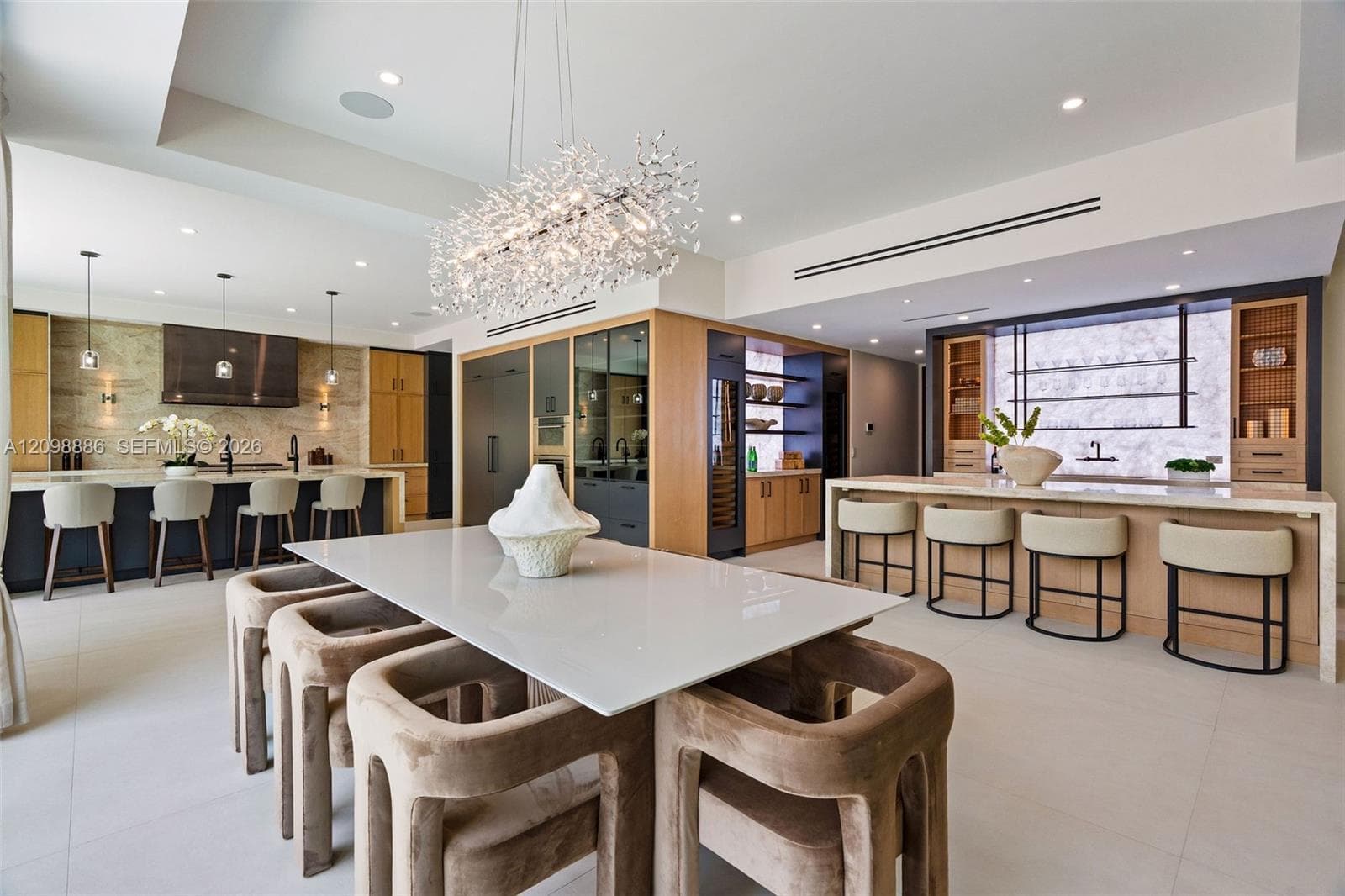 Gourmet kitchen featuring quartz countertops, wood-finish cabinetry, a geometric crystal chandelier, integrated wine refrigeration, and large-format tile flooring