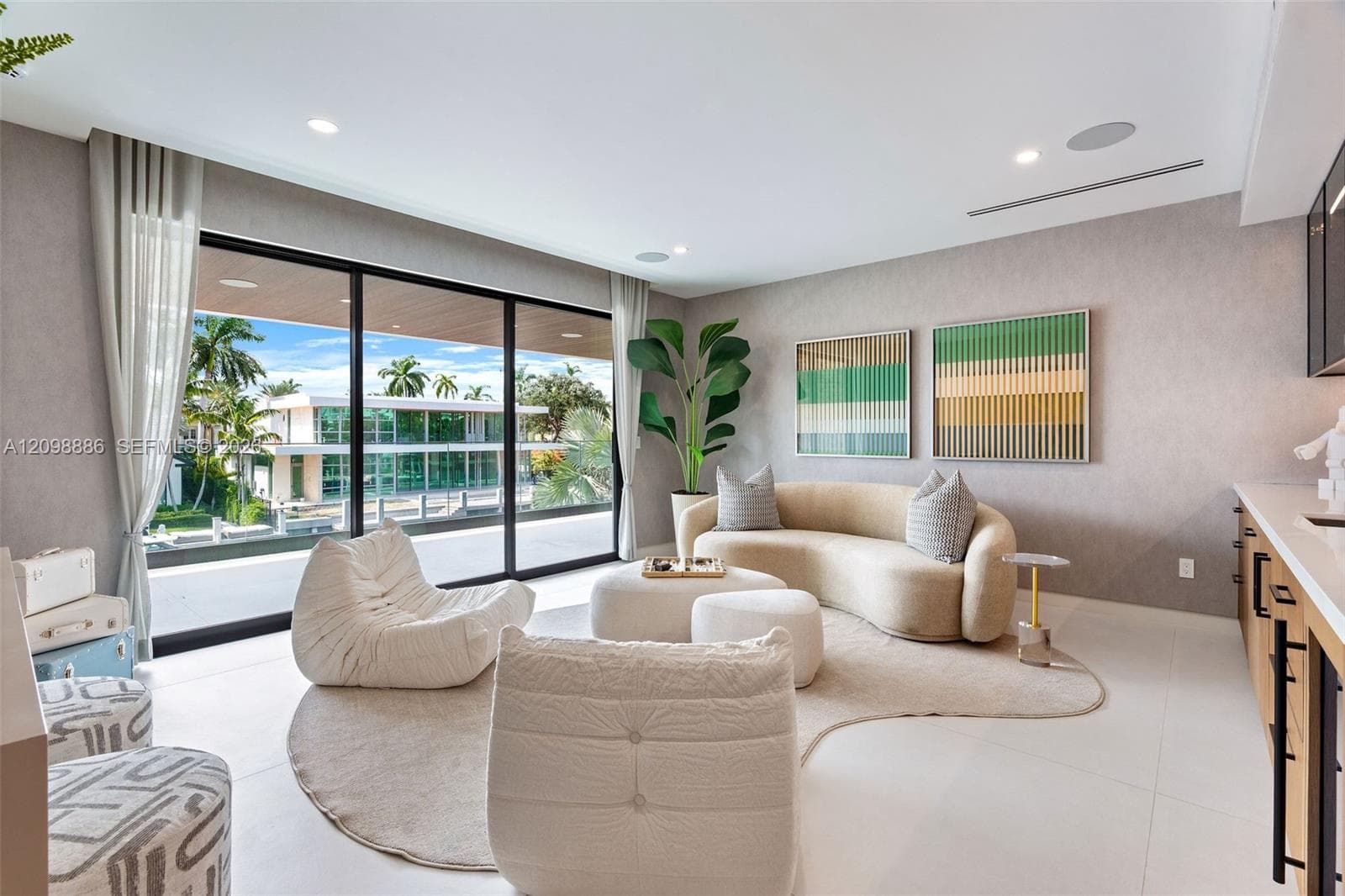 Floor-to-ceiling sliding glass walls, recessed ceiling lighting, light-toned oversized tile flooring, built-in cabinetry, and integrated ceiling speakers