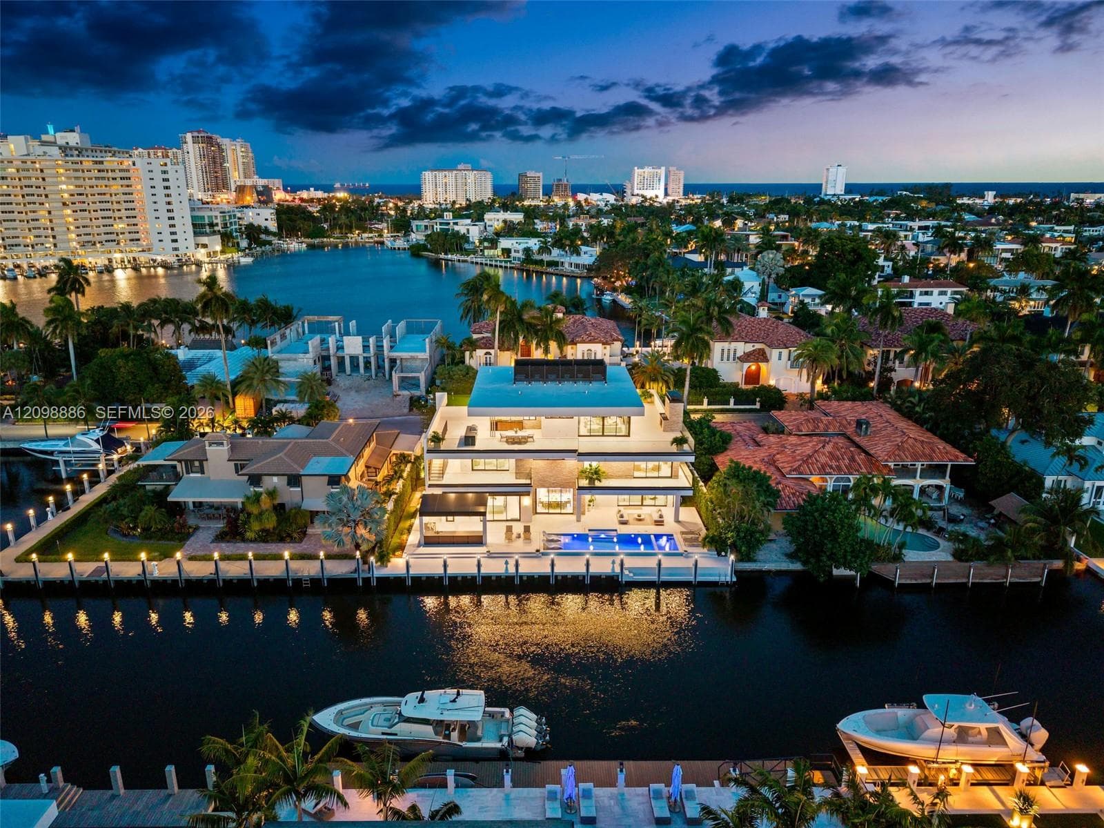 Multi-level waterfront estate featuring a rectangular swimming pool, concrete seawall, private boat dock, and exterior balcony spaces