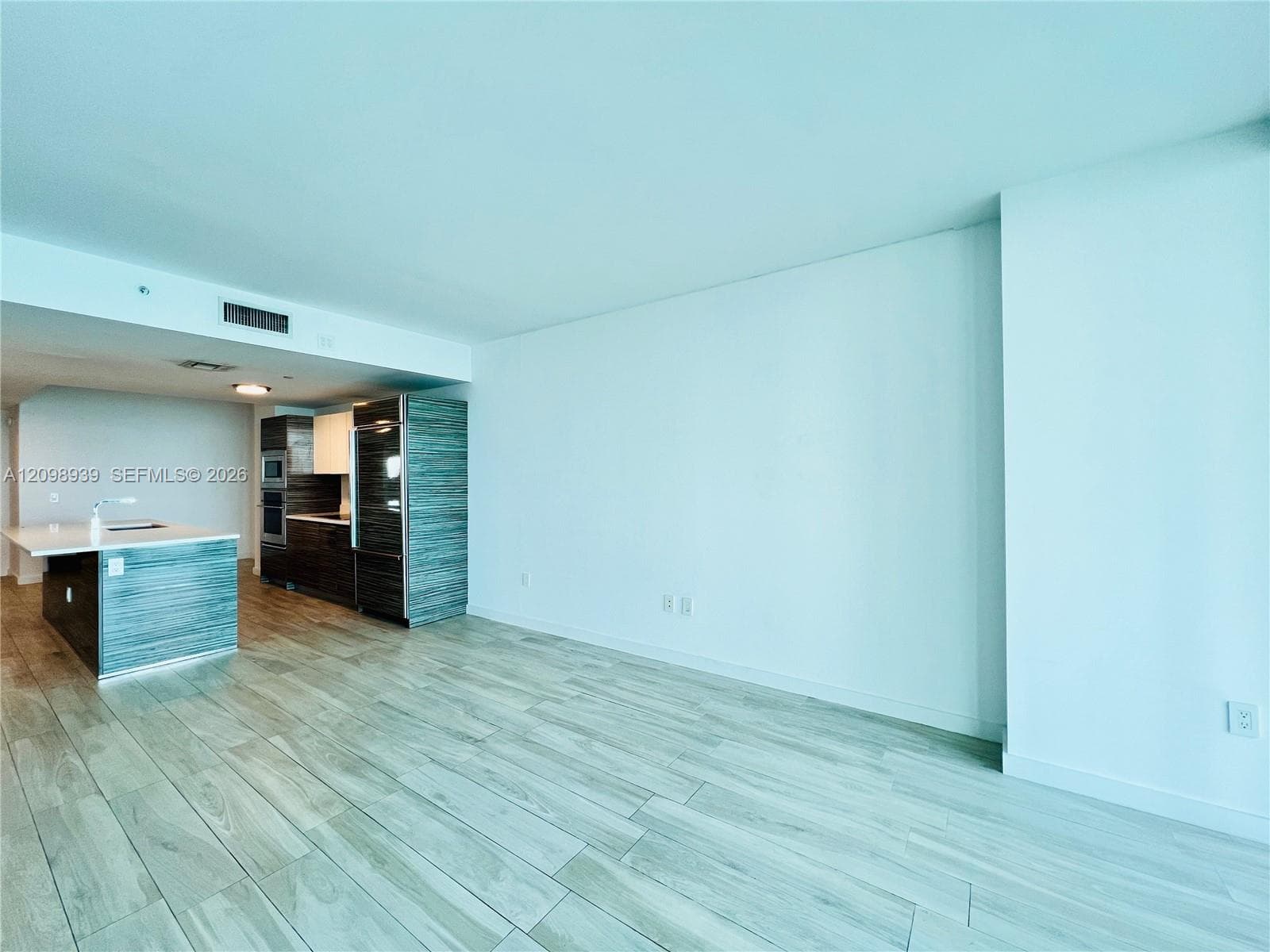 Wood-finish flooring throughout, kitchen island with built-in sink, modern cabinetry, built-in oven, and a built-in refrigerator